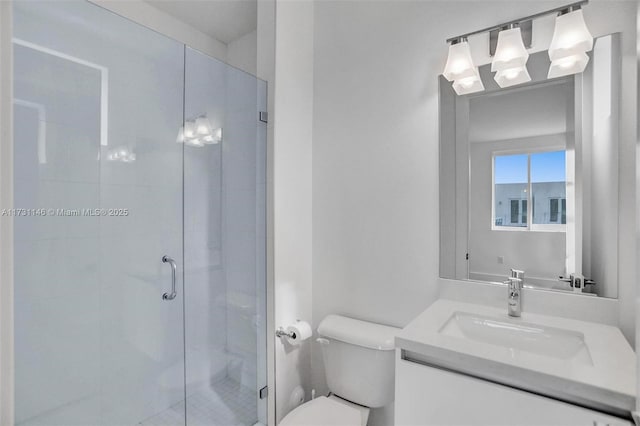 bathroom featuring vanity, a shower with door, and toilet