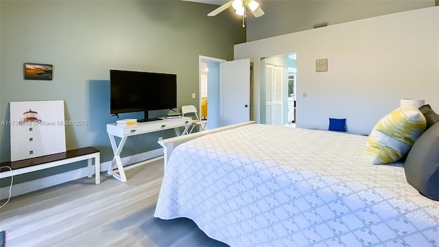 bedroom with ceiling fan, hardwood / wood-style floors, and a towering ceiling