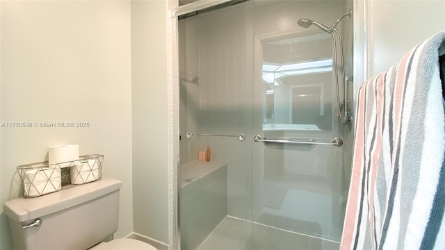 bathroom featuring a shower with shower door and toilet