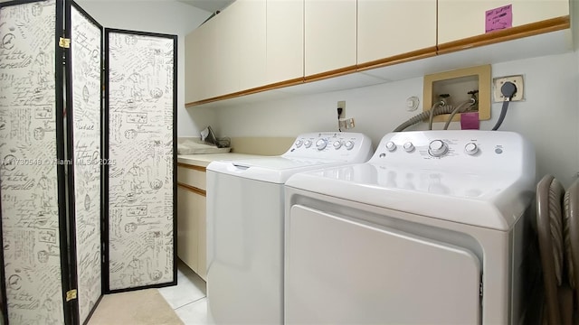 laundry area with light tile patterned floors, cabinets, and washer and dryer