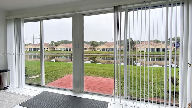 doorway to outside featuring a water view and light tile patterned flooring