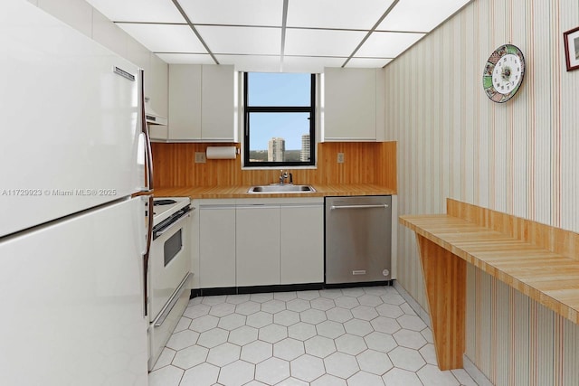 kitchen with sink, white appliances, white cabinetry, and a paneled ceiling