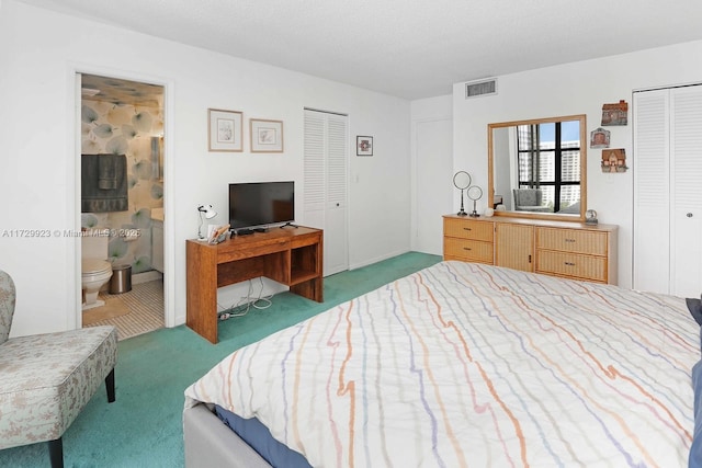 carpeted bedroom with two closets, a textured ceiling, and ensuite bath