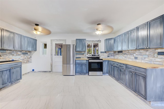 kitchen featuring appliances with stainless steel finishes, decorative light fixtures, butcher block counters, decorative backsplash, and ceiling fan