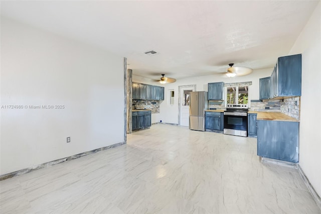 kitchen featuring appliances with stainless steel finishes, tasteful backsplash, wooden counters, blue cabinets, and ceiling fan