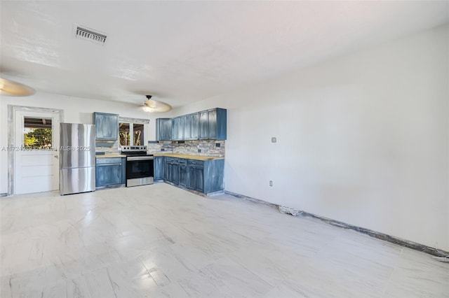 kitchen featuring blue cabinets, ceiling fan, appliances with stainless steel finishes, and decorative backsplash