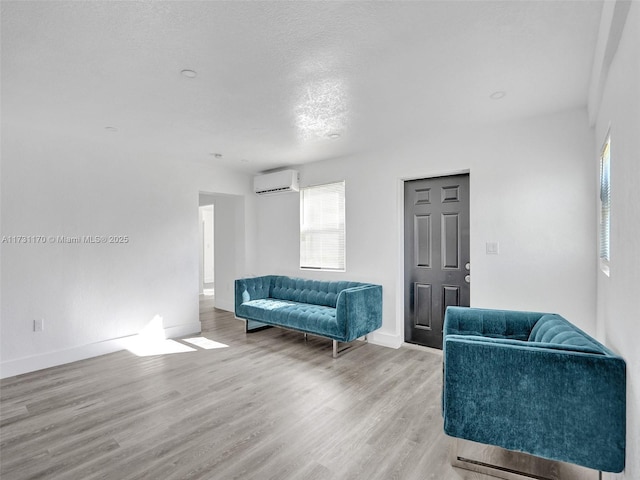 sitting room with a textured ceiling, wood-type flooring, and a wall mounted AC