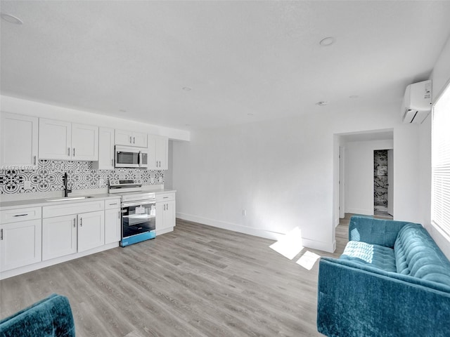 kitchen with sink, electric range, a wall mounted AC, and white cabinets