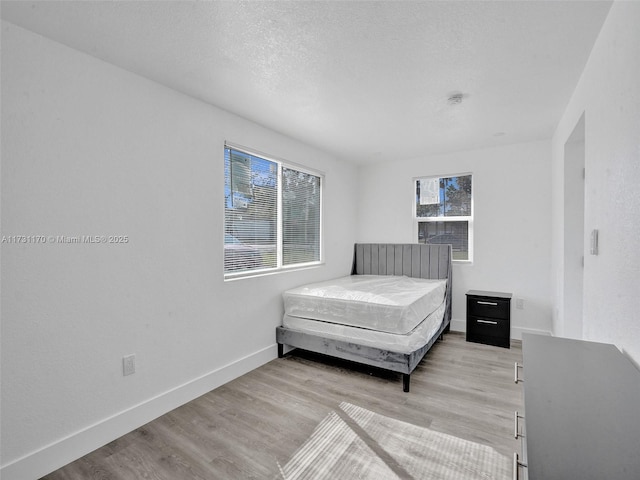 bedroom featuring a textured ceiling and light hardwood / wood-style floors