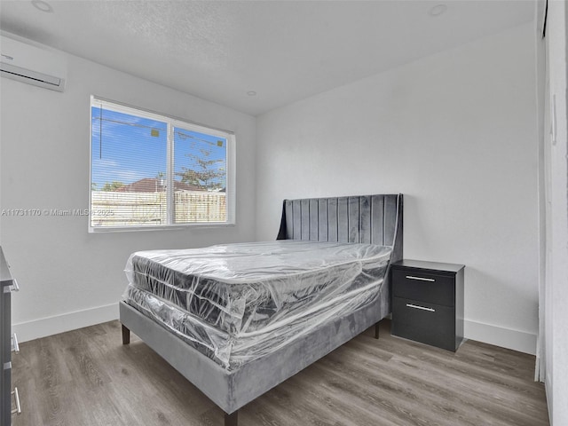 bedroom featuring a wall mounted air conditioner and hardwood / wood-style flooring