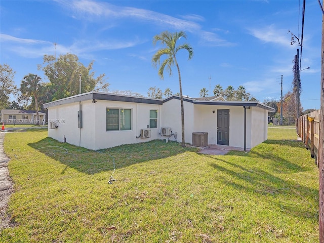 back of house with central AC unit and a lawn