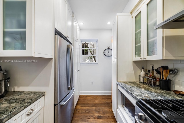 kitchen with white cabinetry, dark wood-type flooring, stainless steel fridge, and dark stone counters