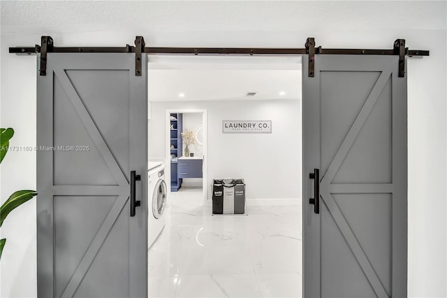 interior space with a barn door, baseboards, marble finish floor, and laundry area