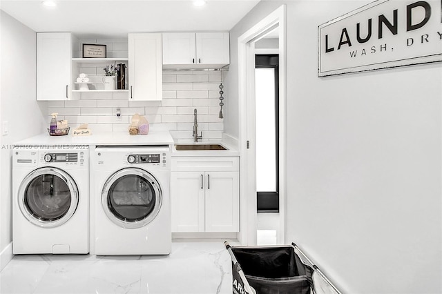 laundry area with cabinet space, washing machine and dryer, marble finish floor, and a sink