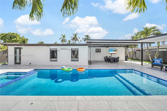 view of pool featuring a patio area, fence, and a pool with connected hot tub