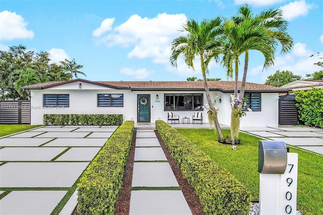 ranch-style house with stucco siding, a porch, a front yard, and fence