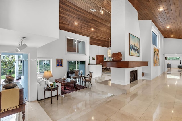 interior space with a towering ceiling, rail lighting, and wooden ceiling