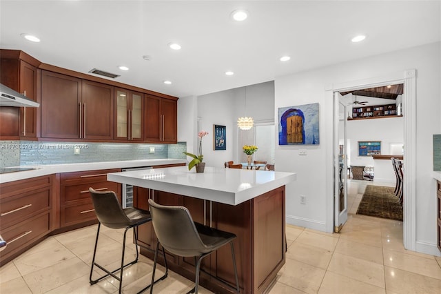 kitchen featuring a breakfast bar, decorative backsplash, hanging light fixtures, a center island, and light tile patterned floors