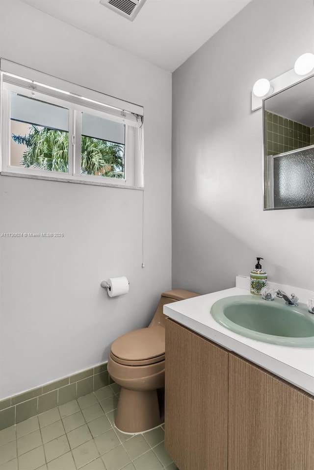 bathroom featuring vanity, tile patterned flooring, a shower with shower door, and toilet