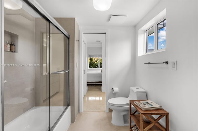 bathroom featuring bath / shower combo with glass door, toilet, tile patterned flooring, and a wealth of natural light