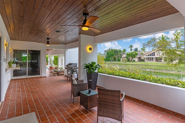 view of patio / terrace featuring a water view, area for grilling, and ceiling fan