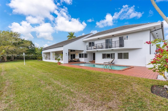 rear view of property with a balcony, a yard, and a patio area