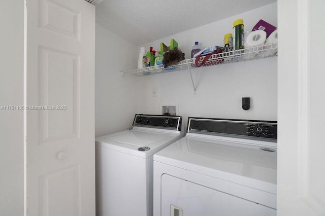 clothes washing area with a textured ceiling and independent washer and dryer