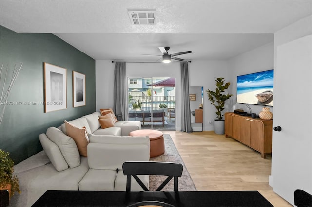 living room with ceiling fan, light hardwood / wood-style floors, and a textured ceiling