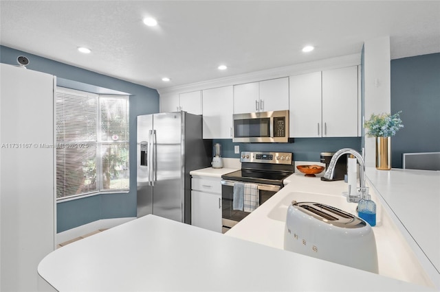 kitchen with stainless steel appliances, kitchen peninsula, sink, and white cabinets