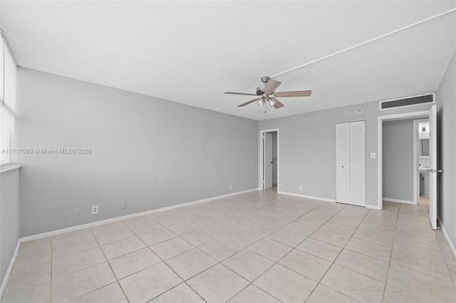 tiled empty room with ceiling fan and a textured ceiling