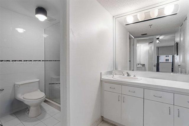 bathroom with tile patterned floors, toilet, a textured ceiling, vanity, and a shower with door