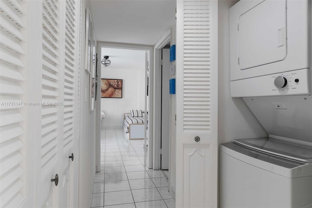 laundry area with stacked washing maching and dryer and light tile patterned floors