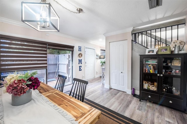 dining room featuring a notable chandelier, crown molding, a textured ceiling, and wood-type flooring