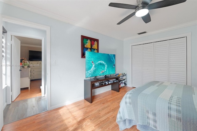 bedroom with light wood-type flooring, ceiling fan, ornamental molding, and a closet