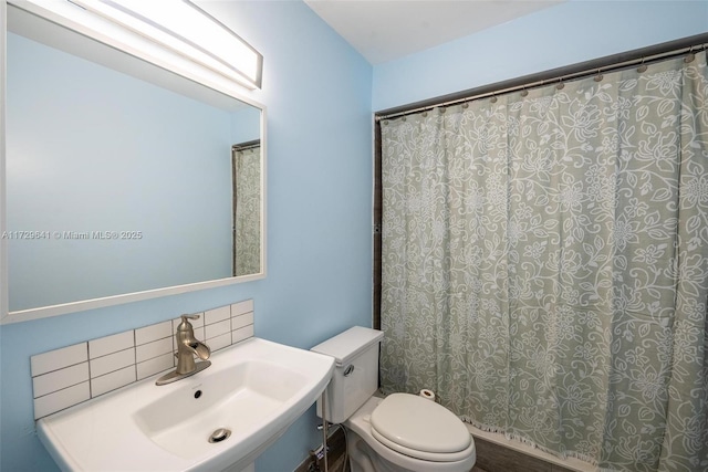 bathroom featuring sink, backsplash, and toilet