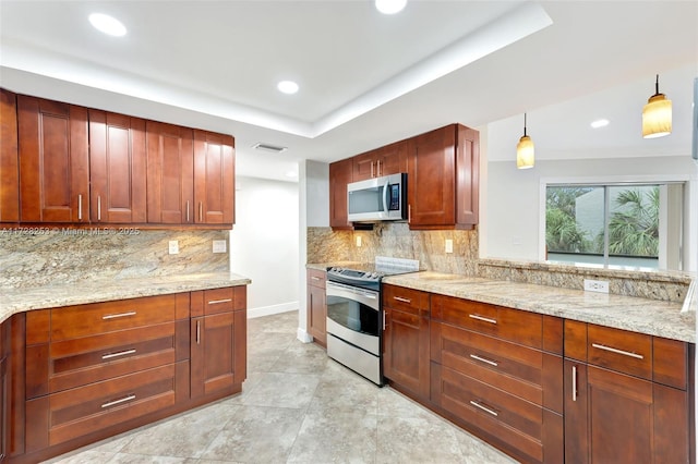 kitchen featuring hanging light fixtures, backsplash, stainless steel appliances, light stone counters, and a tray ceiling