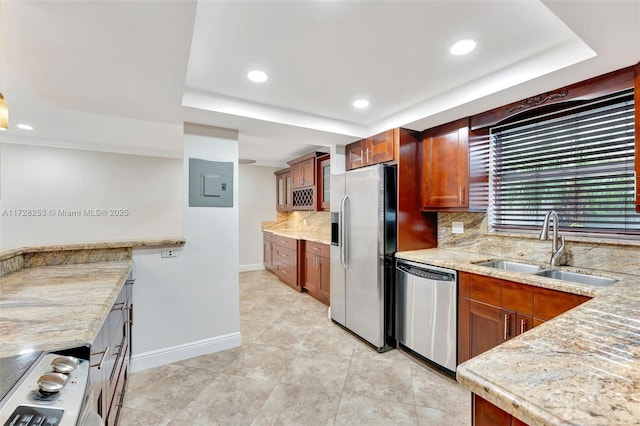 kitchen featuring sink, stainless steel appliances, electric panel, light stone counters, and a tray ceiling