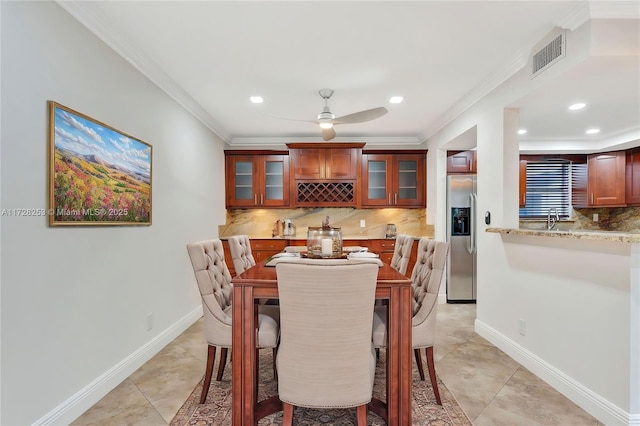 tiled dining area with sink, crown molding, and ceiling fan