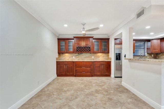 kitchen with tasteful backsplash, ornamental molding, stainless steel fridge, and light stone counters