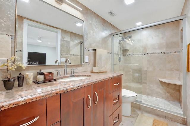 bathroom featuring walk in shower, vanity, toilet, and tile walls