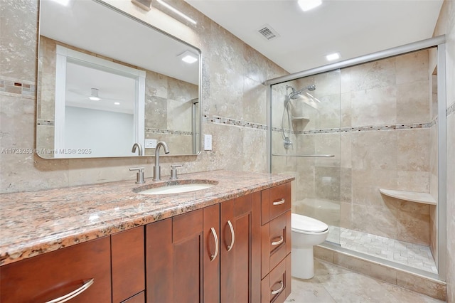 bathroom with vanity, a shower with shower door, tile walls, and toilet