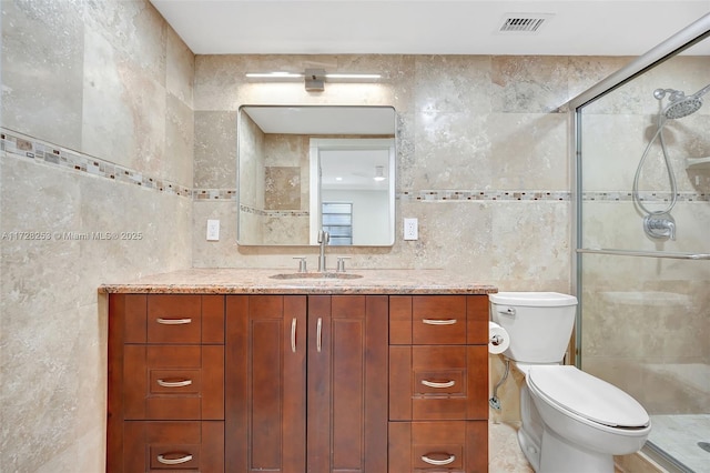 bathroom with tile walls, an enclosed shower, vanity, and toilet