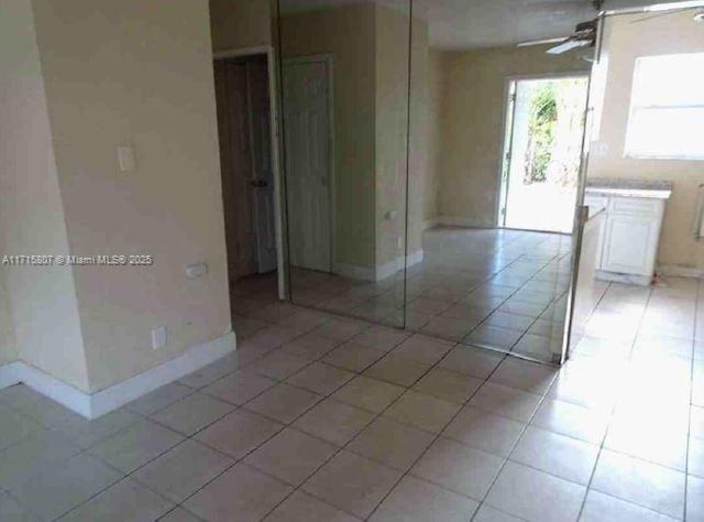 tiled empty room featuring ceiling fan