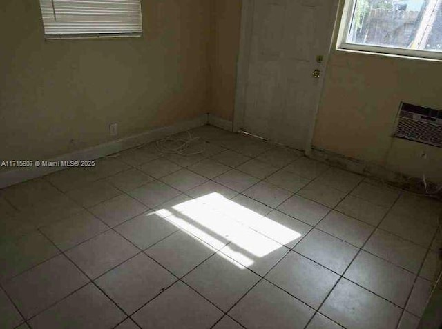 empty room featuring a wall unit AC and light tile patterned floors