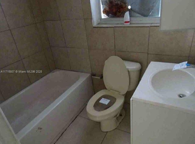 bathroom featuring vanity, tile patterned flooring, a bathing tub, and toilet