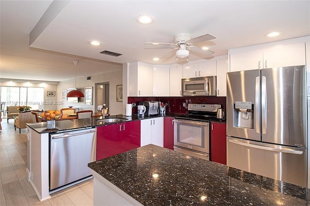 kitchen with white cabinetry, stainless steel appliances, kitchen peninsula, and sink