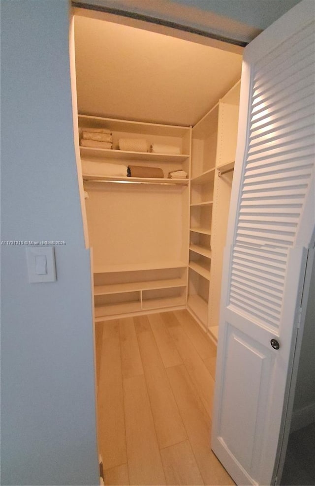 walk in closet with lofted ceiling and light hardwood / wood-style floors