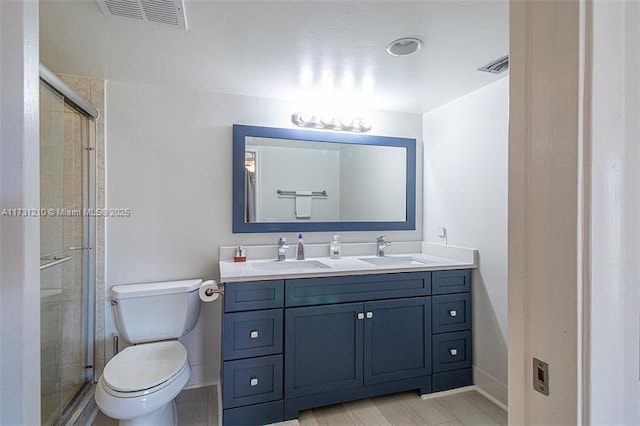 bathroom featuring vanity, a shower with shower door, and toilet