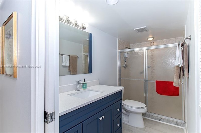 bathroom featuring toilet, vanity, and a shower with shower door