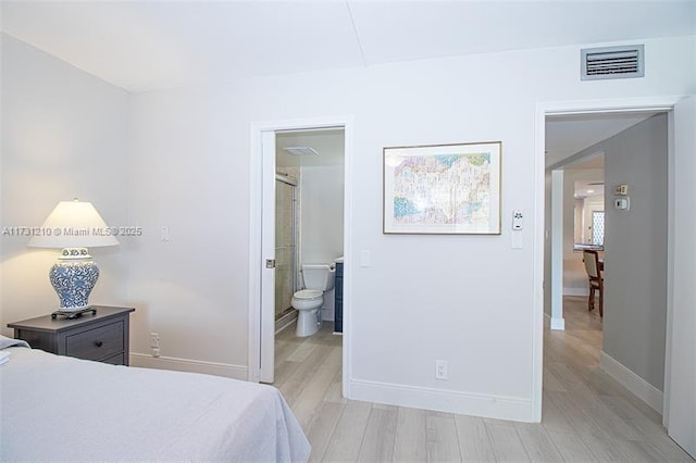 bedroom with connected bathroom and light hardwood / wood-style floors